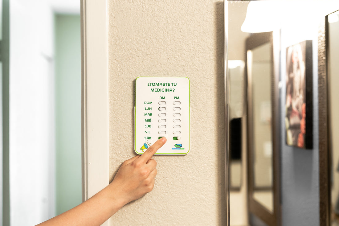 Hand pressing a digital pill reminder on a refrigerator door.