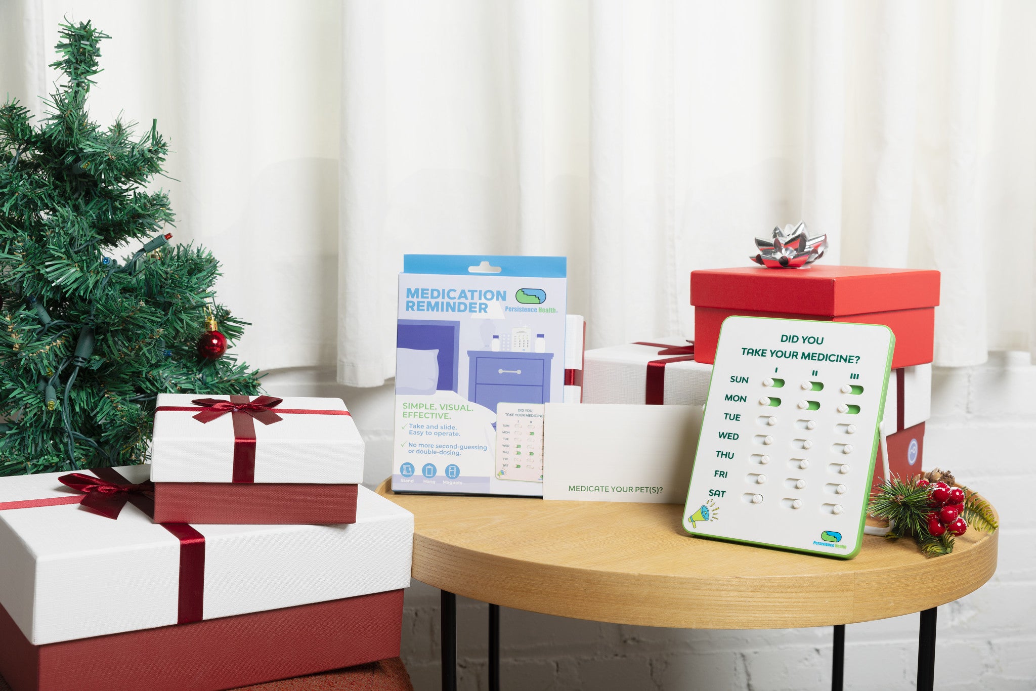 Christmas-themed setting with presents, a tree, and a medication reminder device on a table.