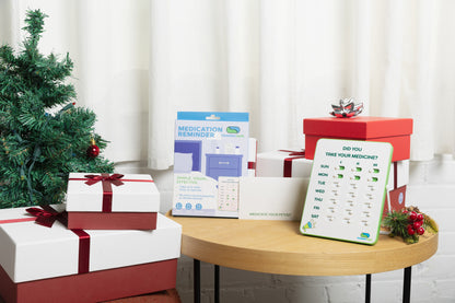 Christmas-themed setting with presents, a tree, and a medication reminder device on a table.