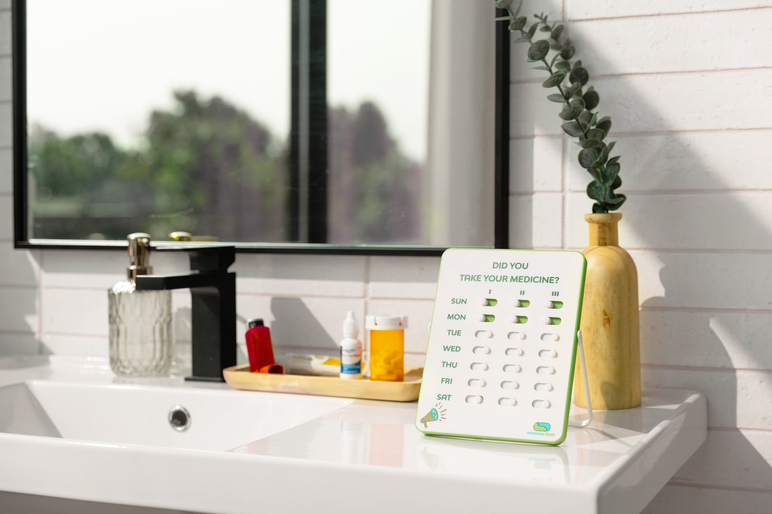Medication reminder device on a bathroom counter with a sink and window in the background